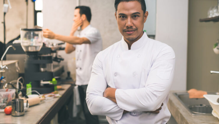 Smiling young asian chef in the kitchen interior. Chef Jobs in Europe For Indians